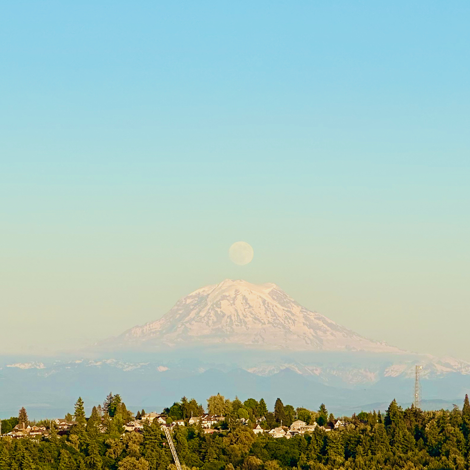 Full moon resting on the summit of Mt. Rainier